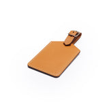 Tan full-grain leather luggage tag, flat lay, angled view — personalised travel accessory — CarveOn, made in Ireland